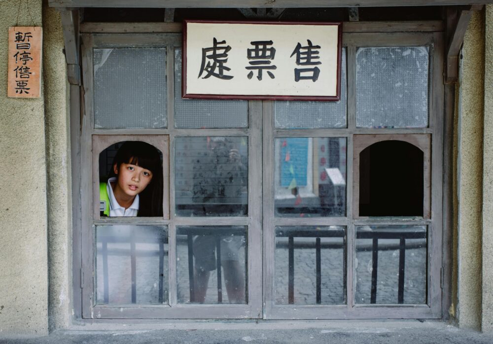 A person looks out of a window with Chinese signs.