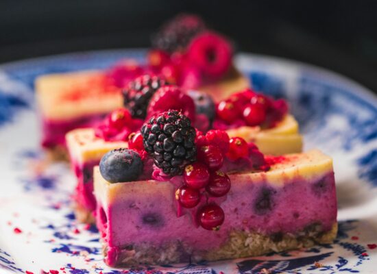 Colorful berry cheesecake slices on a decorative blue plate.