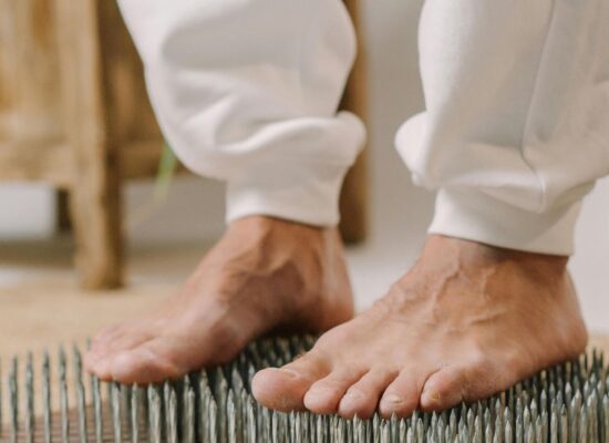 Person standing barefoot on a bed of nails for therapy.