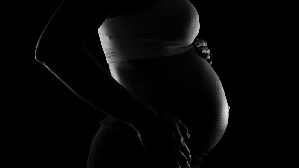 A silhouette of a pregnant person cradling their belly.