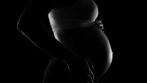 A silhouette of a pregnant person cradling their belly.