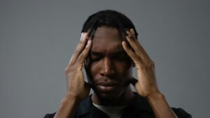 Person with hands on temples, eyes closed, appearing stressed or thoughtful.