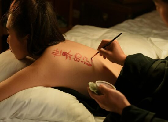 A person is painting red calligraphy on another person's back.