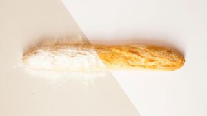 A baguette with flour on a two-tone background surface.