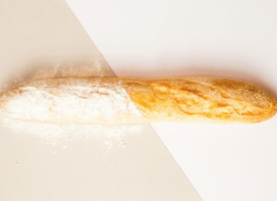 A baguette with flour on a two-tone background surface.