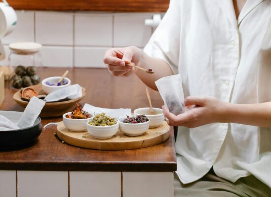 Person preparing tea with various dried herbs and flowers.