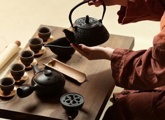A person performs a traditional tea ceremony with a teapot and cups.