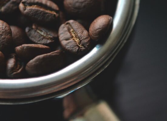 Close-up of coffee beans in a metal portafilter, dark background.
