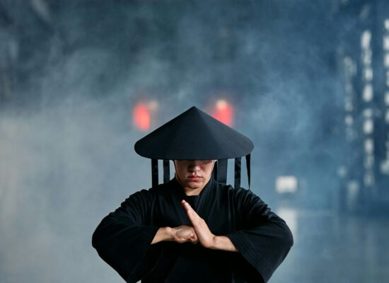 Person in black robe and hat, misty industrial background, meditating.
