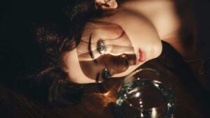 Person lying on floor, dramatic lighting, glass of water nearby.