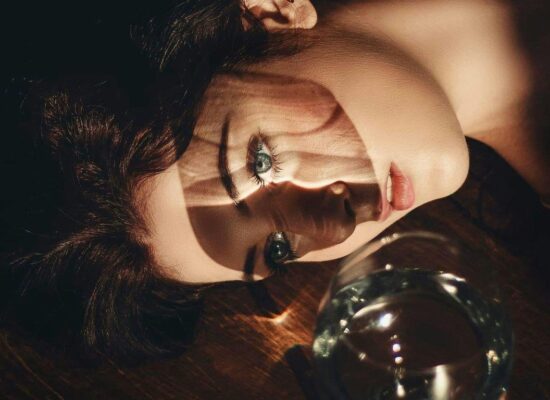 Person lying on floor, dramatic lighting, glass of water nearby.
