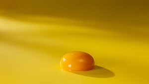 Egg yolk on a yellow surface with soft lighting.