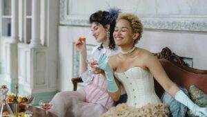 Two people in vintage attire enjoying drinks and snacks.