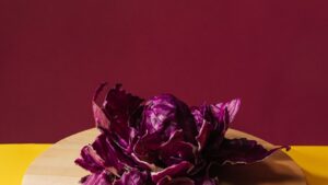 Purple cabbage on wooden board, yellow and burgundy background.
