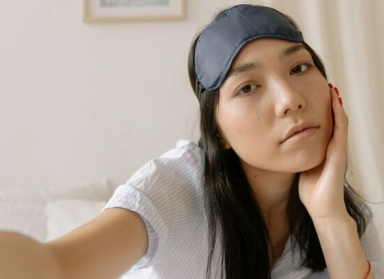 Person with sleep mask on head, sitting on bed, relaxed.