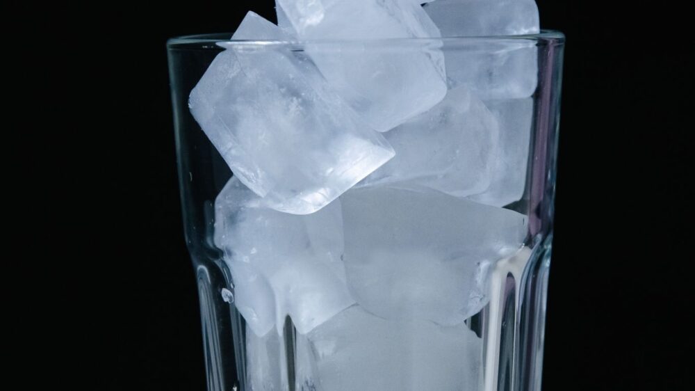 A glass filled with ice cubes against a dark background.