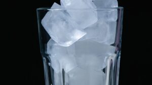 A glass filled with ice cubes against a dark background.
