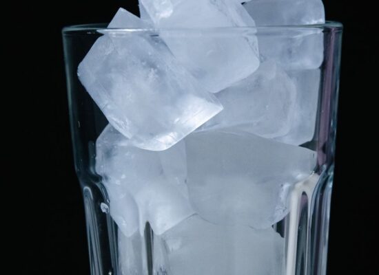 A glass filled with ice cubes against a dark background.