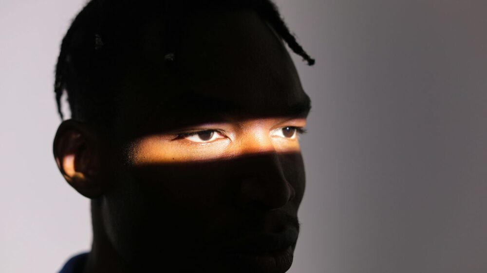 A face partially illuminated by a narrow beam of light.