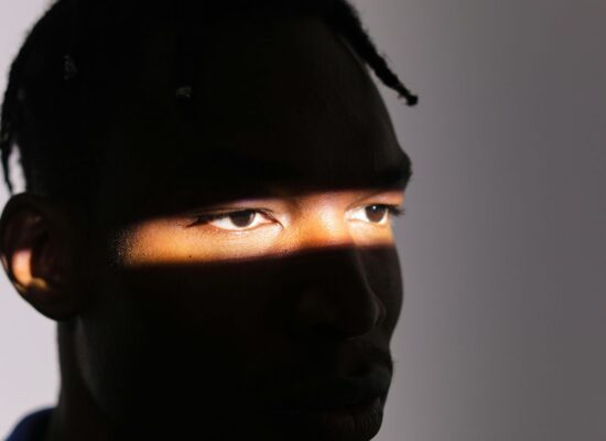 A face partially illuminated by a narrow beam of light.