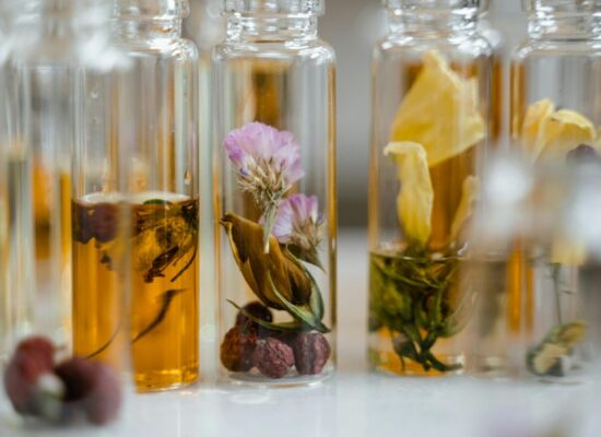 Glass vials filled with dried flowers and amber liquid, arranged closely.