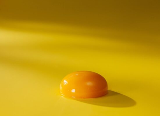 Egg yolk on a yellow surface with soft lighting.