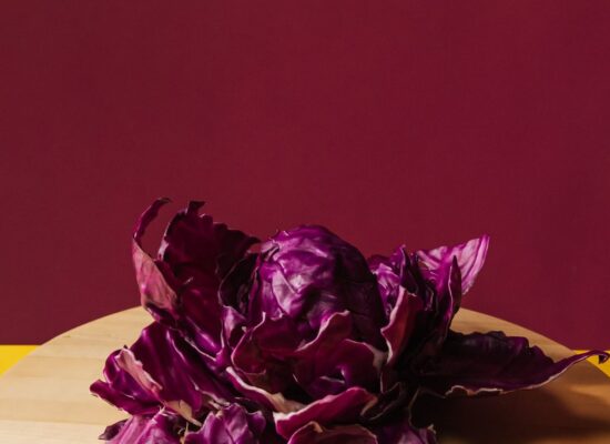 Purple cabbage on wooden board, yellow and burgundy background.